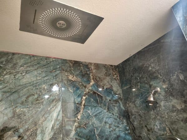 Residential Remodeling by DCB Construction Sacramento Polished porcelain tile on shower with pebble flooring, also showing light built into celing in Sacramento CA