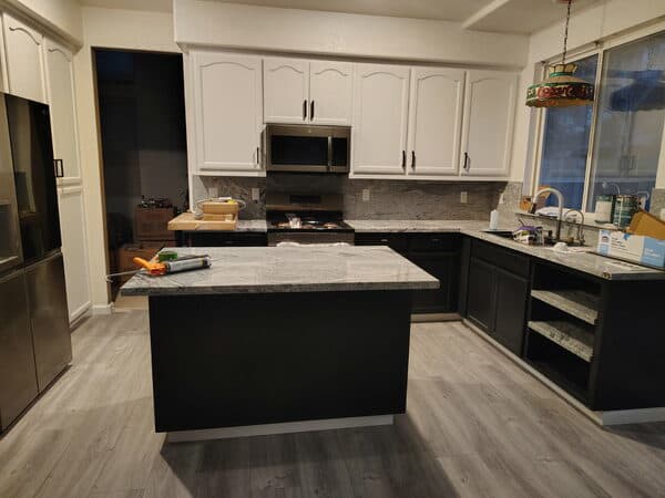 Kitchen Remodeling by DCB Construction Sacramento A newly remodeled kitchen with a contrasting color pallette with a dark gray island and lower cabinets and white upper cabinets and light gray faux wood flooring in Sacramento CA